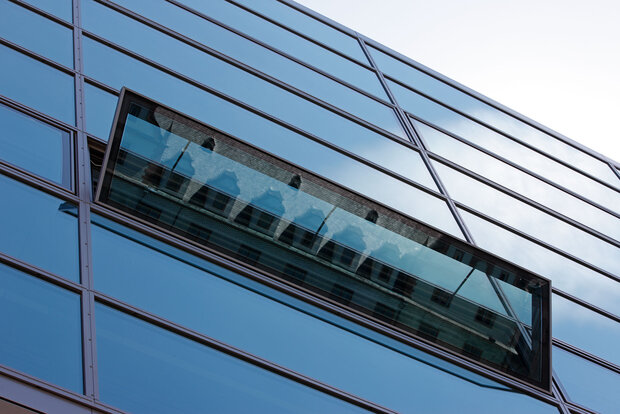 Fensterelement in Glasfassade. Das Fenster ist in Kippstellung geöffnet.